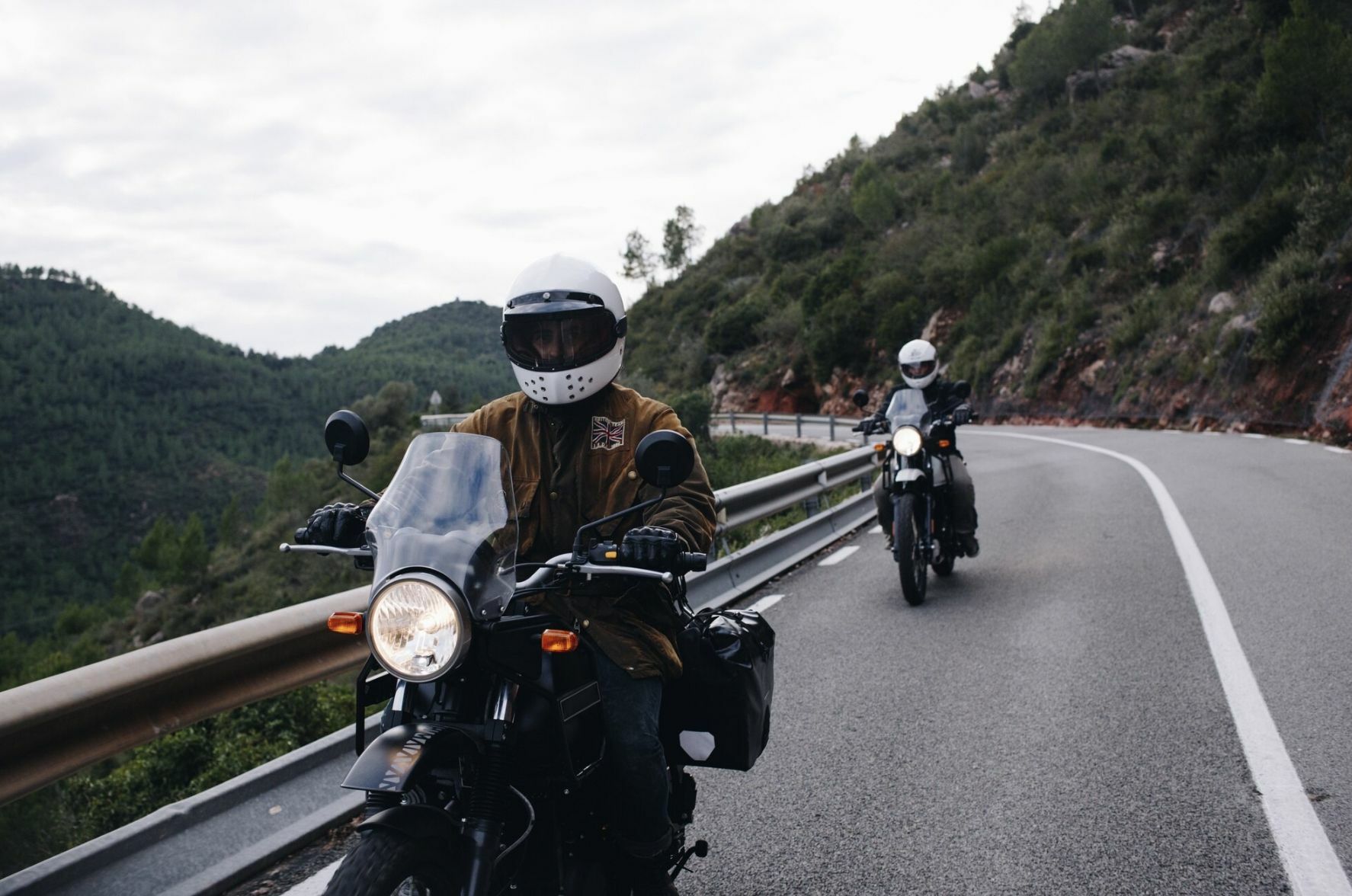 Two men who rent a motorbike in Thailand, riding the motorbike through mountainous roads.