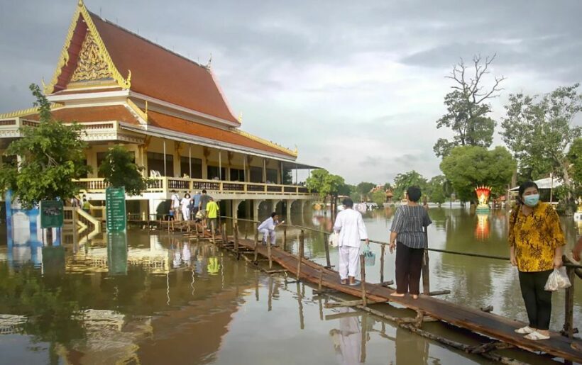 Worshippers wade through floods to get to temple in central Thailand