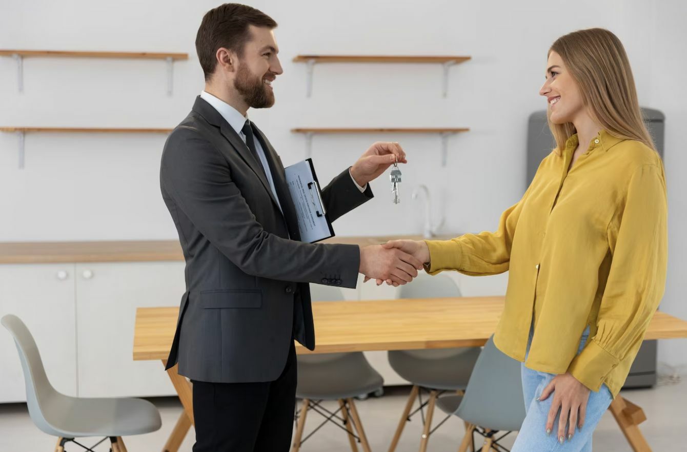 Male real estate agent giving keys to new house to female buyer, buying a condo in Thailand