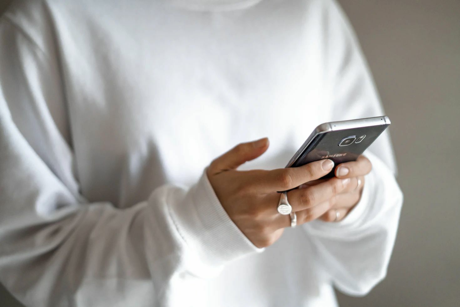 Girl holding Phone wearing white jumper