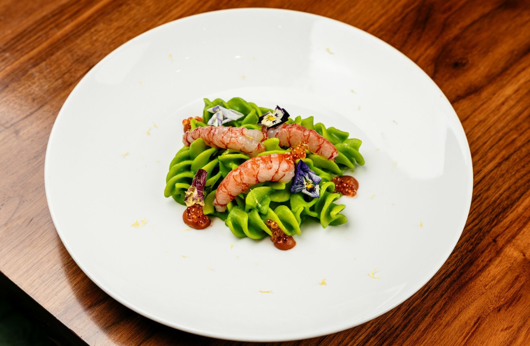 A plate of green pasta with red shrimps. It's Mazzara Fusilli at Rossini's Bangkok.