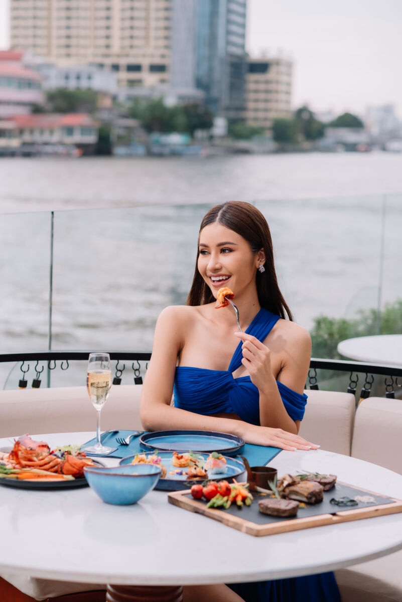A woman eating shrimp by the Chao Phraya river, Riverside Rendez-vous at Siam Yacht Club