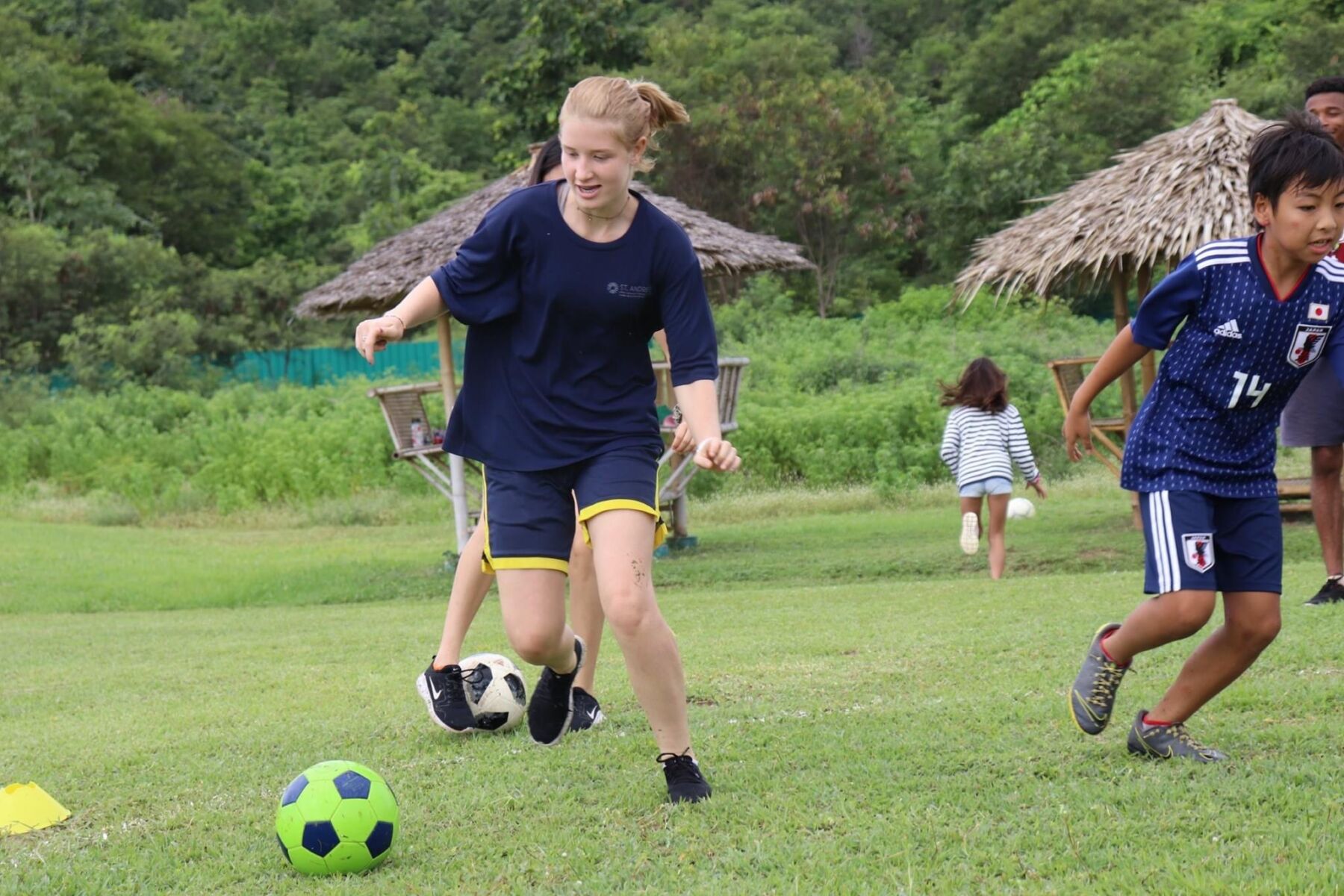 A girl playing soccer during a summer camp, iCamp Thailand.