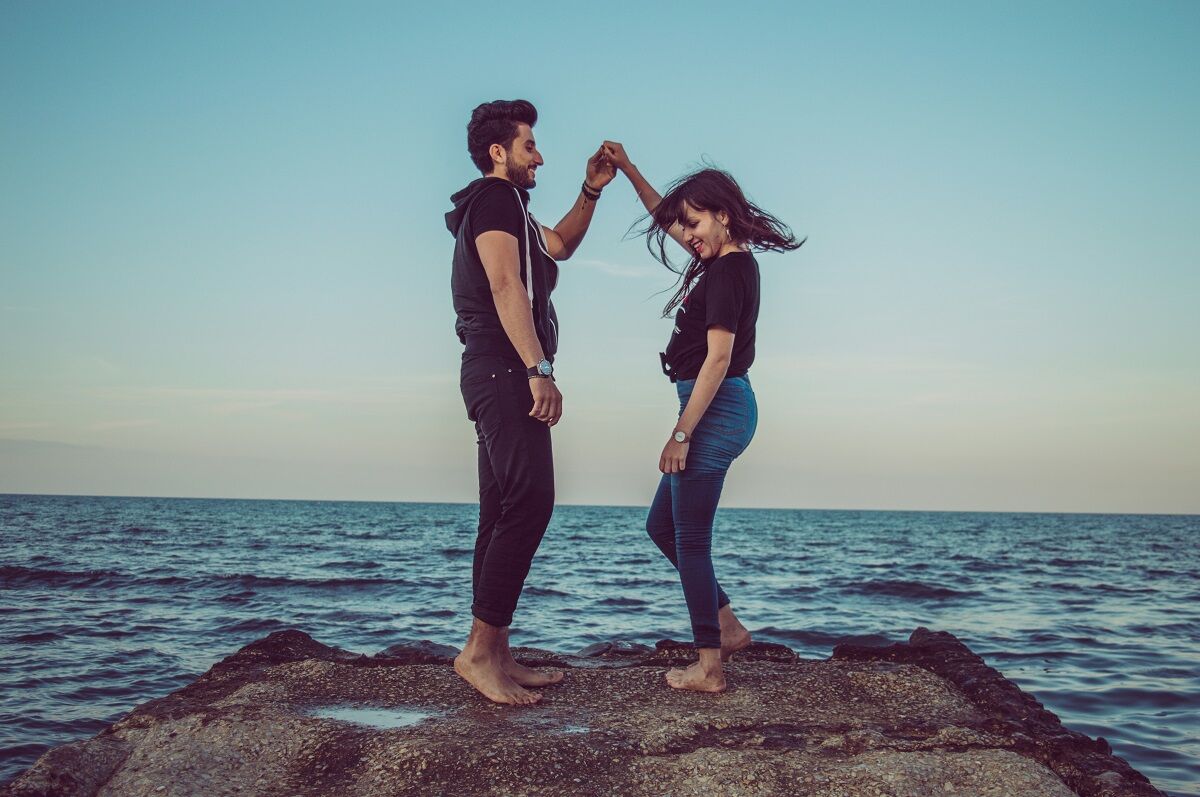 couple standing on a big rock on a beach