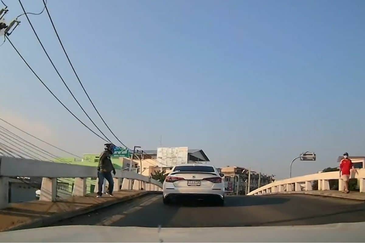 Thai man helps disabled person on bridge