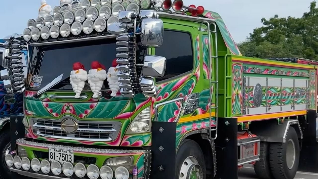 Green modified and painted lorry truck with multiple mirrors, headlights, and Michelin Men