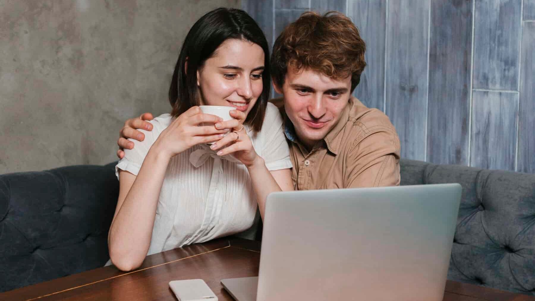 Young couple in front of laptop smiling