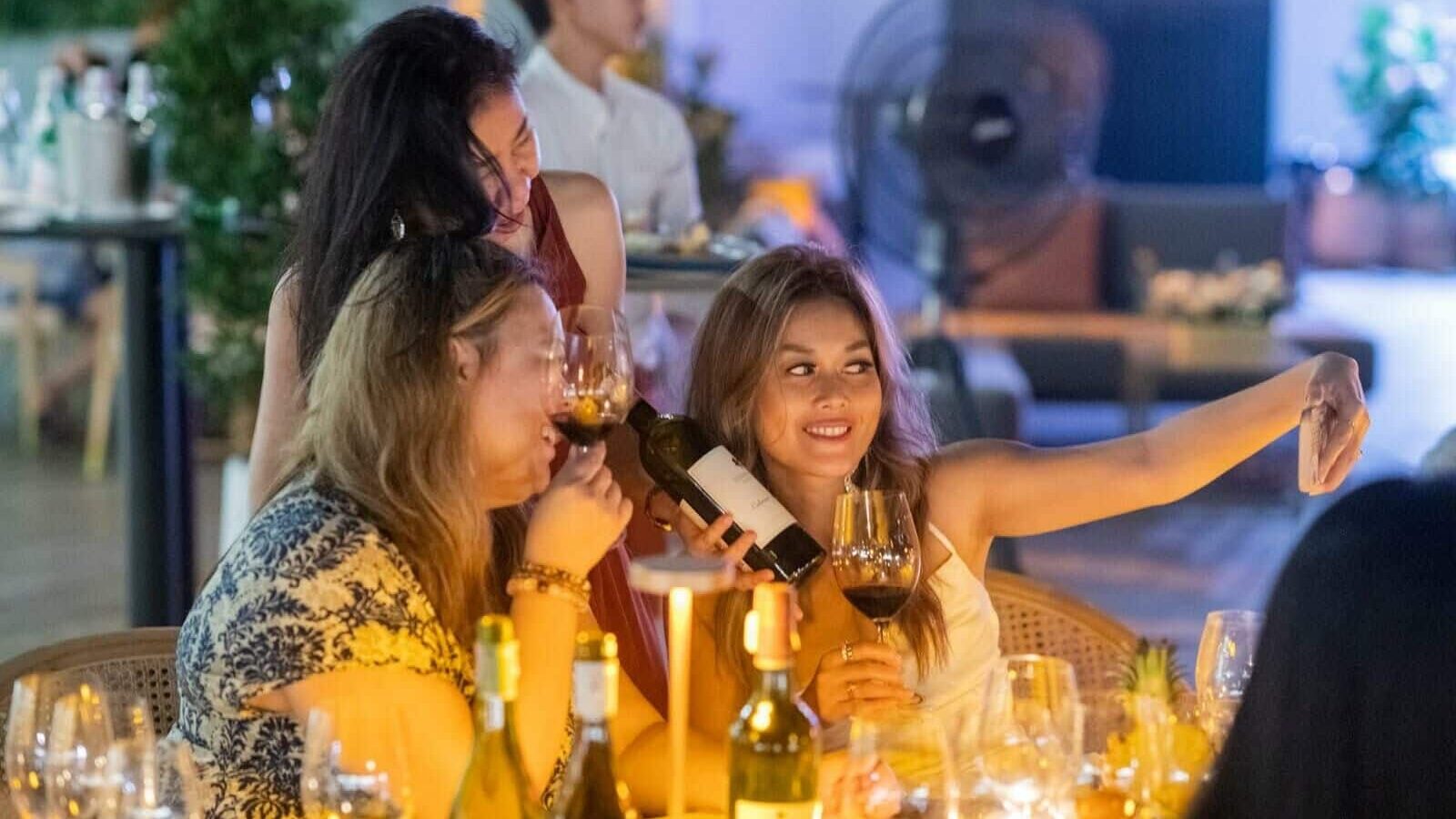 Women enjoying a wine tasting dinner at a beach club in Phuket, Thailand