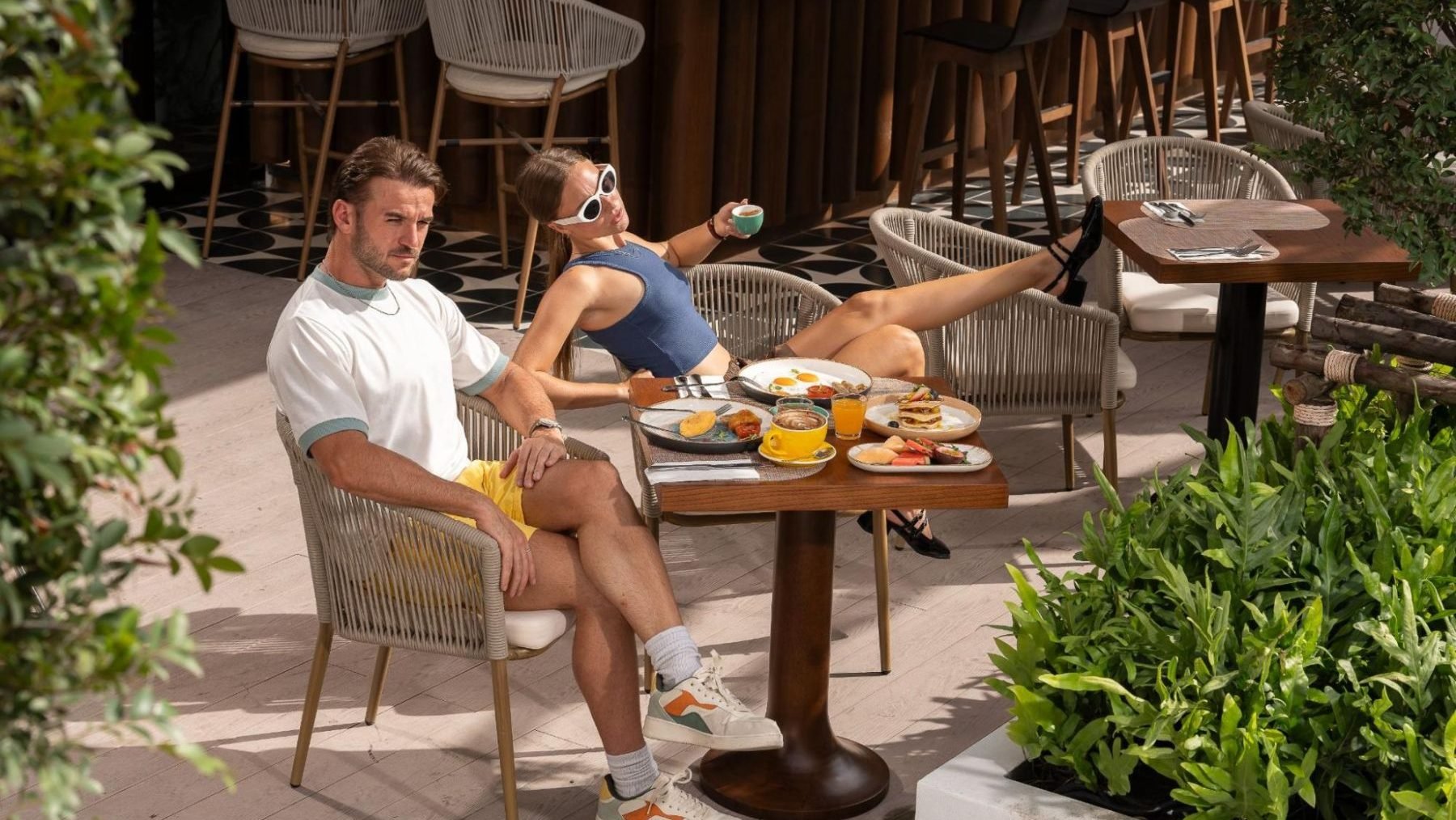 Couple enjoying breakfast with coffee and tropical dishes on the terrace of a new hotel in Phuket