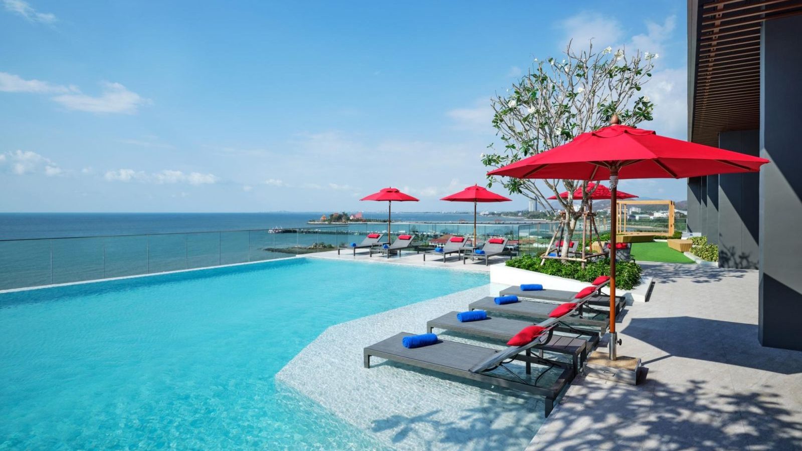 Infinity pool with red umbrellas overlooking the ocean at Novotel Marina Sriracha
