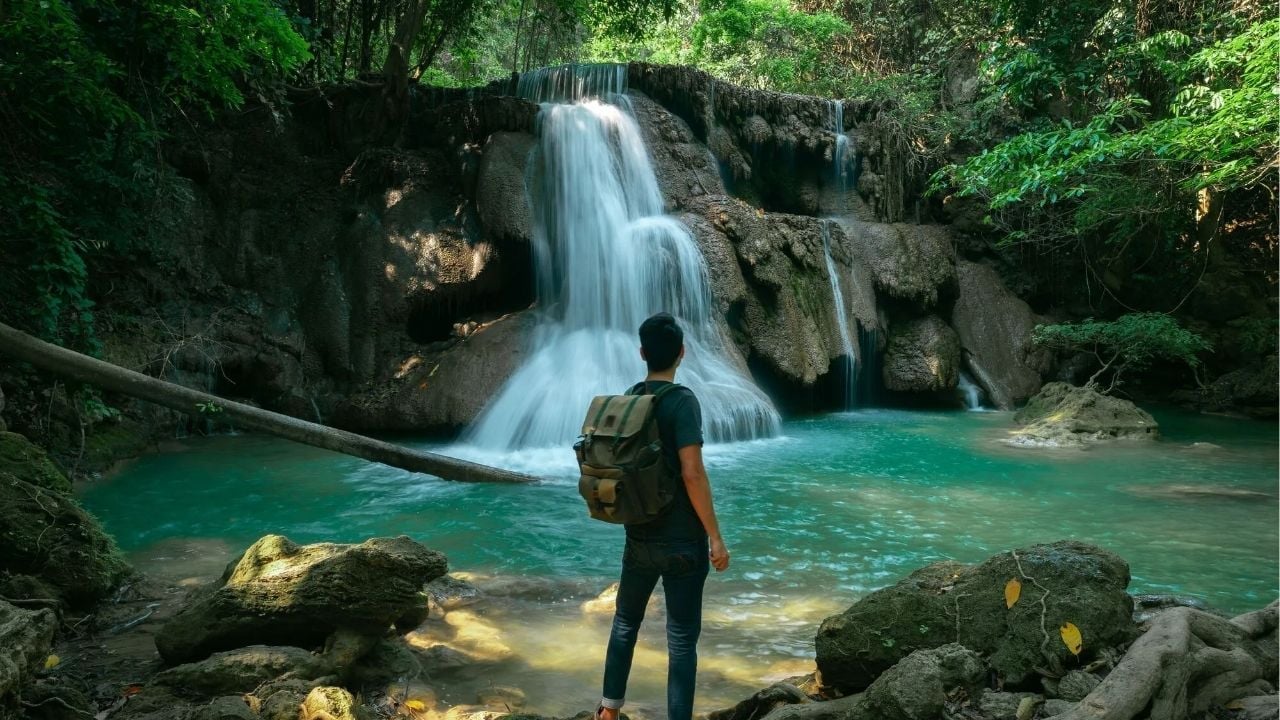 A backpacker by the Kanchanaburi waterfall | Photo taken from the BucketListly Blog website