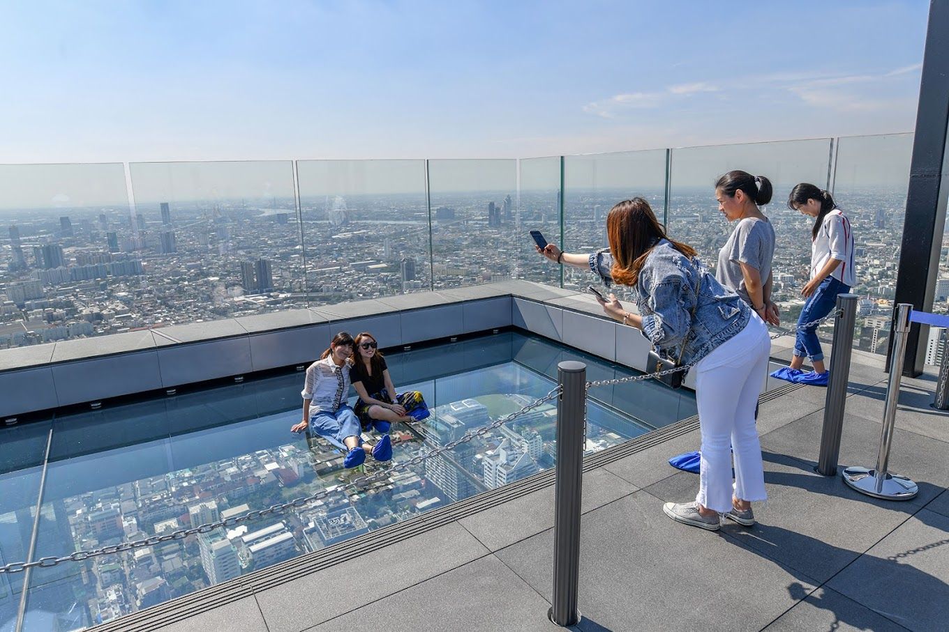 People taking photos on the glass-tray section of King Power Mahanakhon SkyWalk