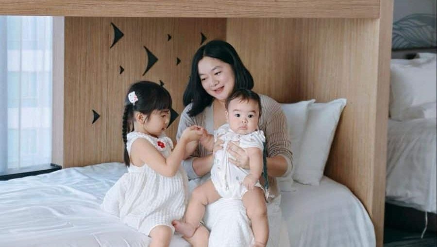 A mother and her two baby daughters on a bed during a holiday