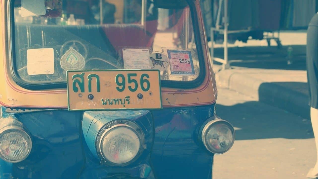 A tuk-tuk with a visible road tax sticker on its windshield.