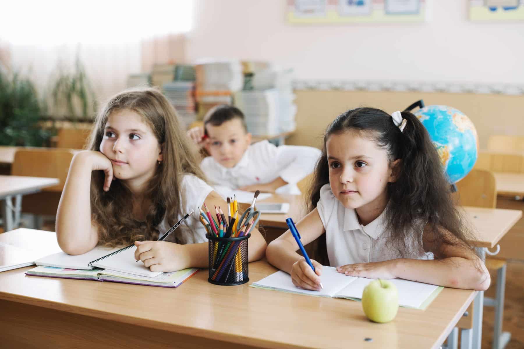 School children studying at lesson holding pens writing, as they move to Thailand