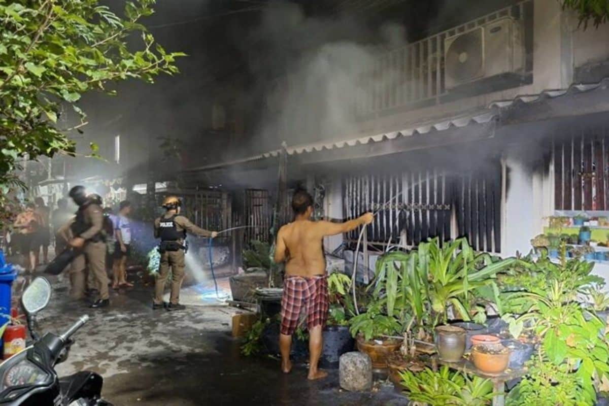 Police and forensic officers investigate a burnt townhouse after a fatal fire in Bangkok