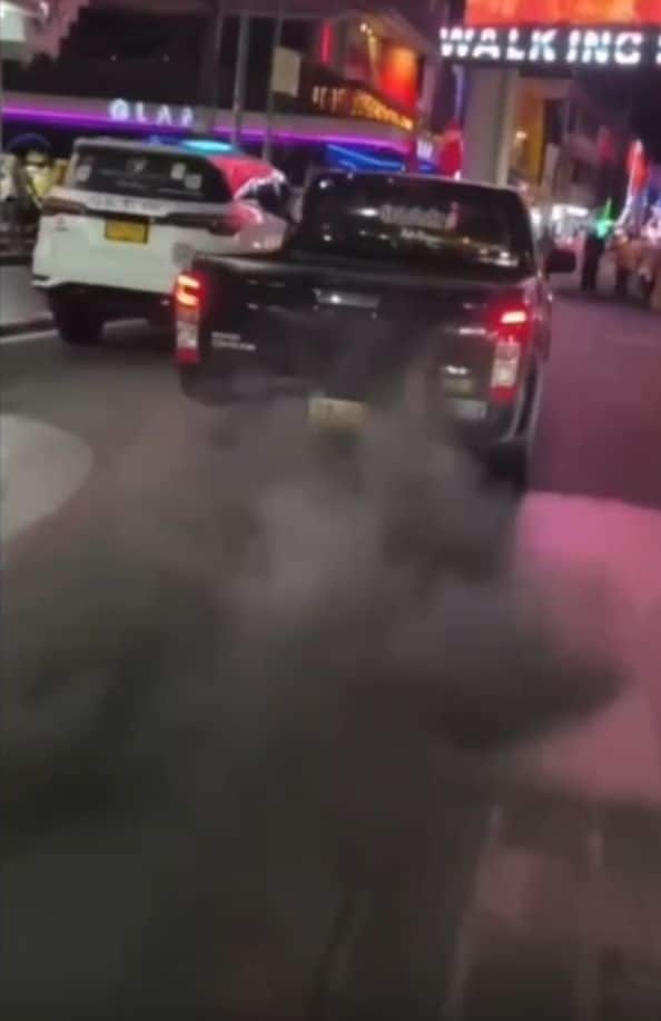 Modified pickup truck emitting thick black smoke near Walking Street in Pattaya