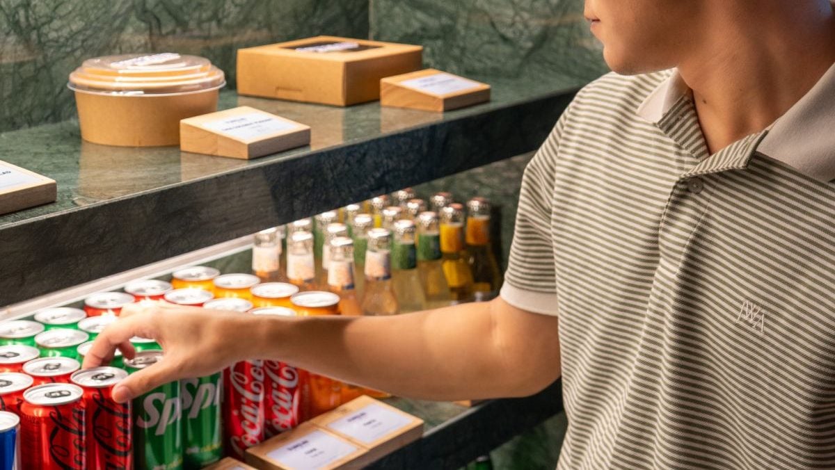 A man taking coca cola from a fridge
