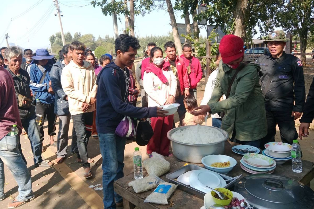 Thai officers giving food and water to Cambodian migrants
