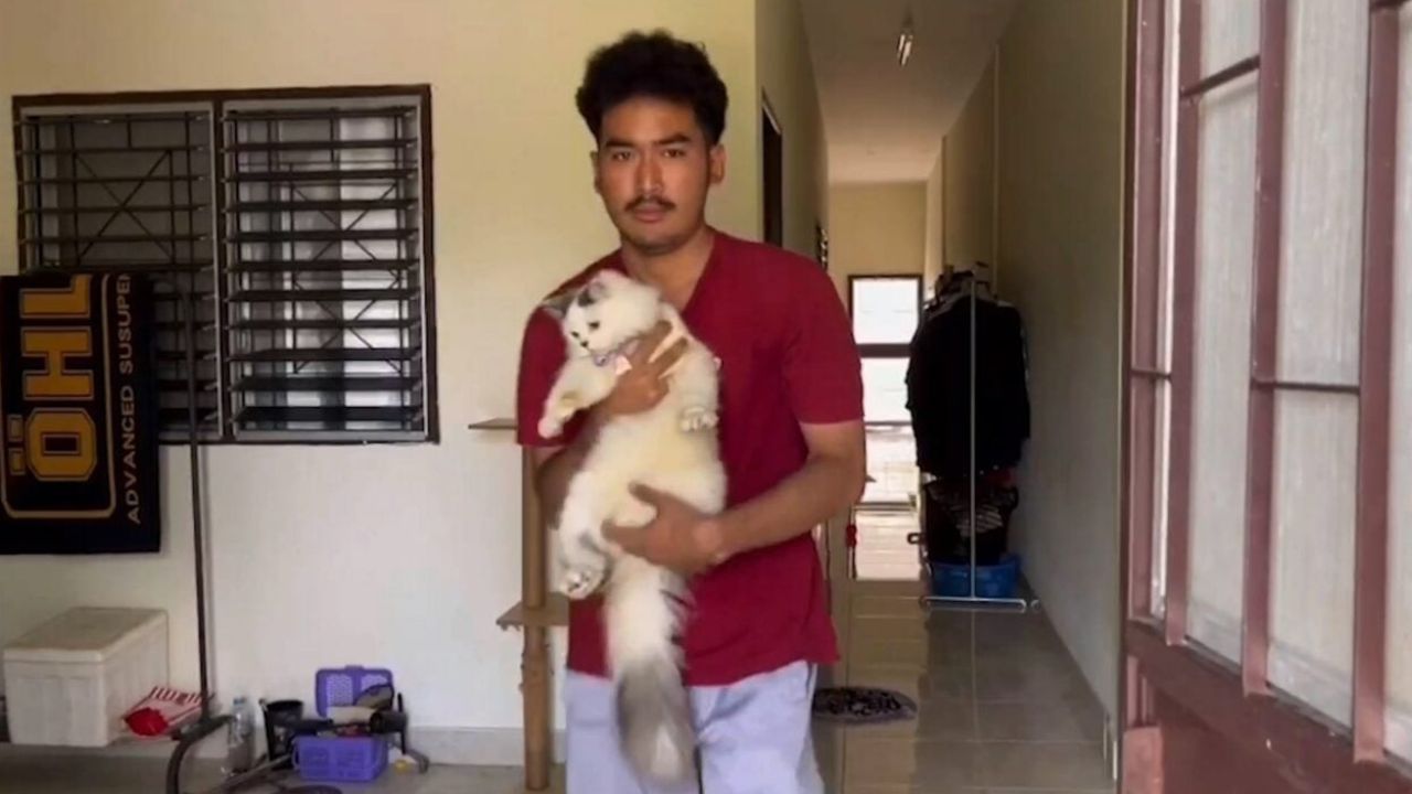 Patchara holding Candy, his surviving Persian cat in Songkhla