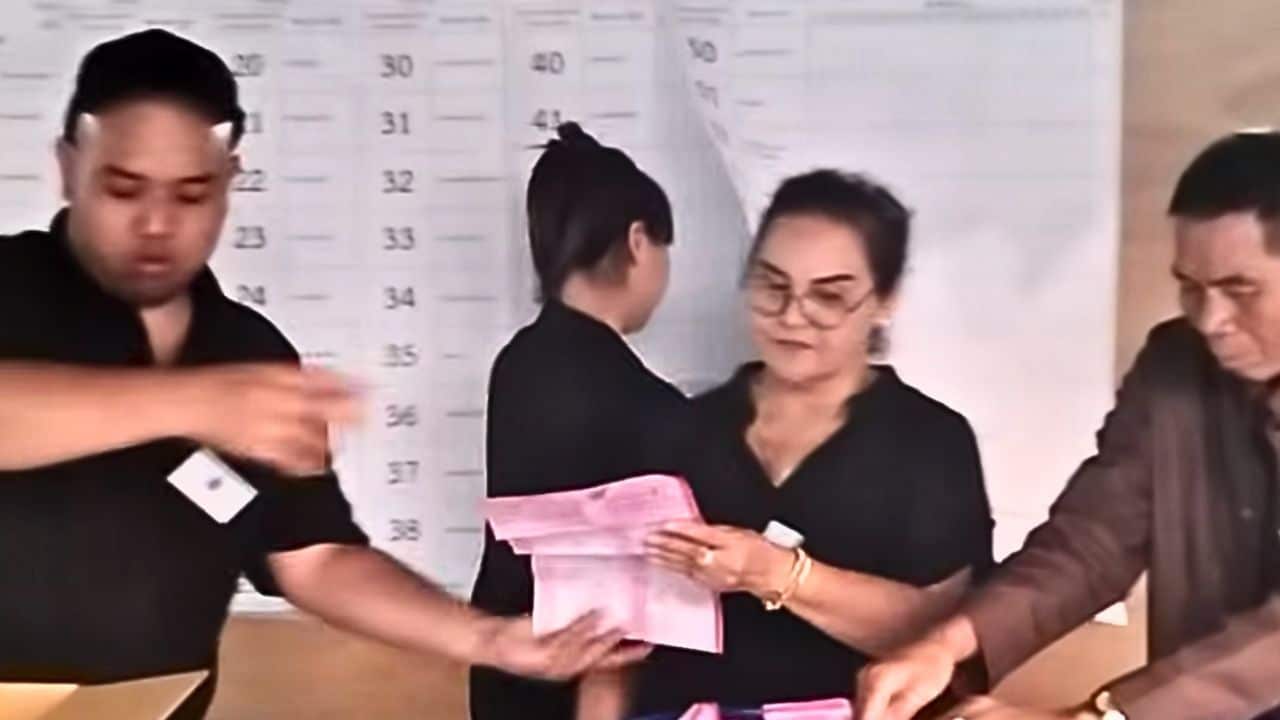 Thai election official writing vote tally behind overlapping papers