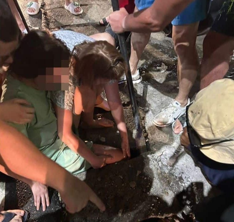 Sakhu Police and bystanders assist a Russian tourist whose right leg is trapped in a drainage opening at Naithon Beach, Phuket.