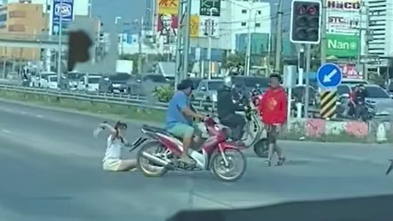 Thai woman sits and throws shoes on road after argument with boyfriend