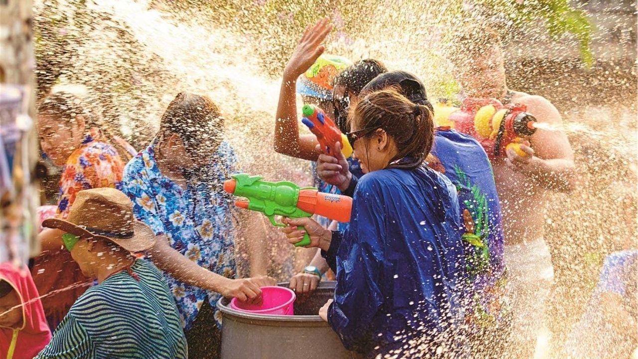 Crowds enjoying water fights during Songkran Thailand celebrations in a bustling city street.
